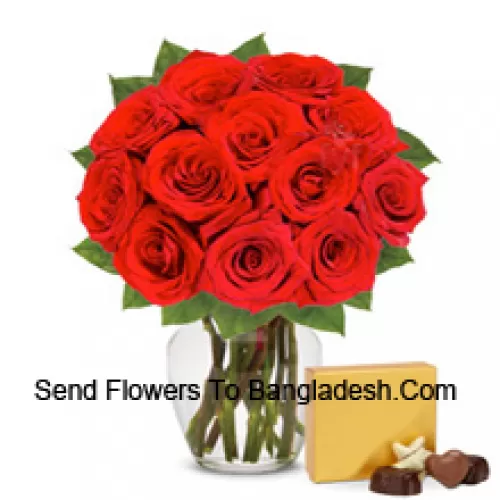12 rote Rosen mit einigen Farnen in einer Glasvase begleitet von einer importierten Schachtel Schokoladen