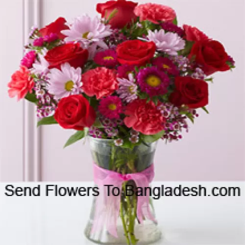 Rosas rojas, claveles rojos y otras flores variadas dispuestas hermosamente en un jarrón de vidrio