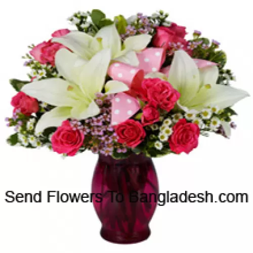 Różowe róże i białe lilie z sezonowymi dodatkami w szklanej wazie