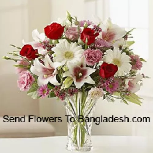Punaiset ruusut, vaaleanpunaiset neilikat, valkoiset gerberat ja valkoiset liljat muiden erilaisten kukkien kanssa lasimaljakossa