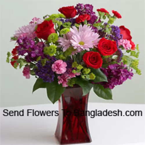 Красные розы, розовые гвоздики и другие разноцветные сезонные цветы в стеклянной вазе